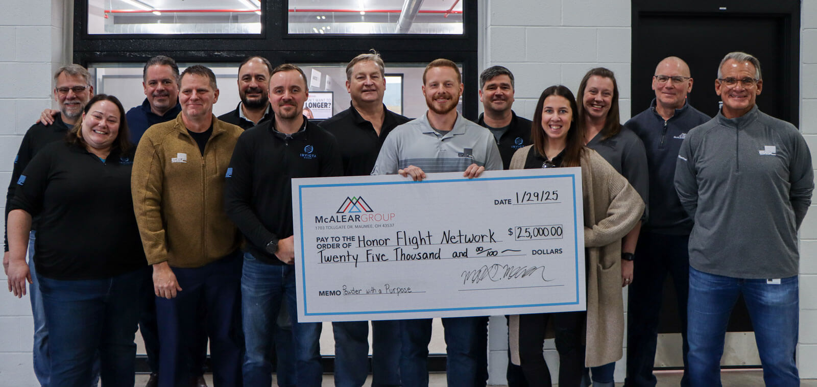 The McAlear Group Executive team holding a large check for $25,000 to Honor Flight Network from Powder with a Purpose